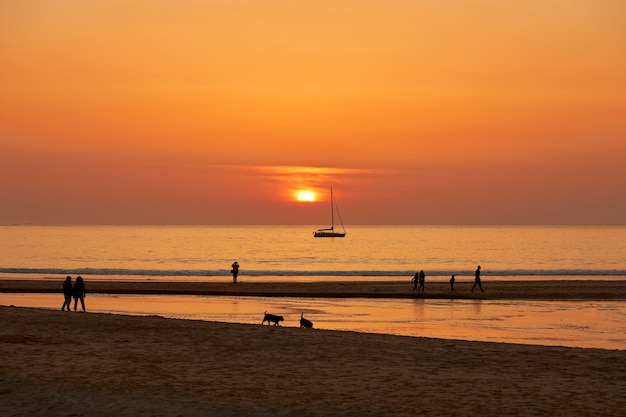 Pôr do sol vermelho com pessoas passeando na praia de Playa America, na Galiza, Espanha.