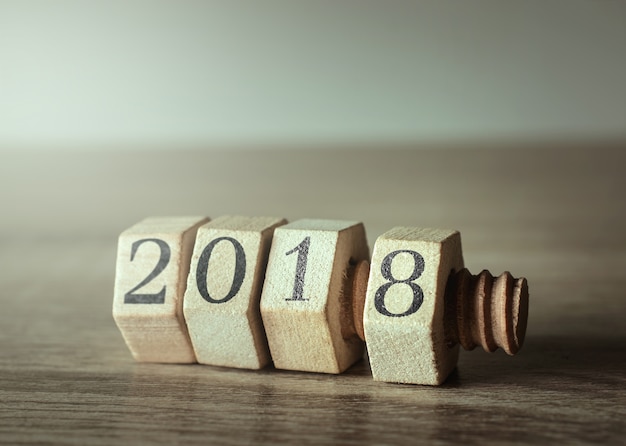 Porca e parafuso de madeira na tabela de madeira com número 2018 do ano novo.