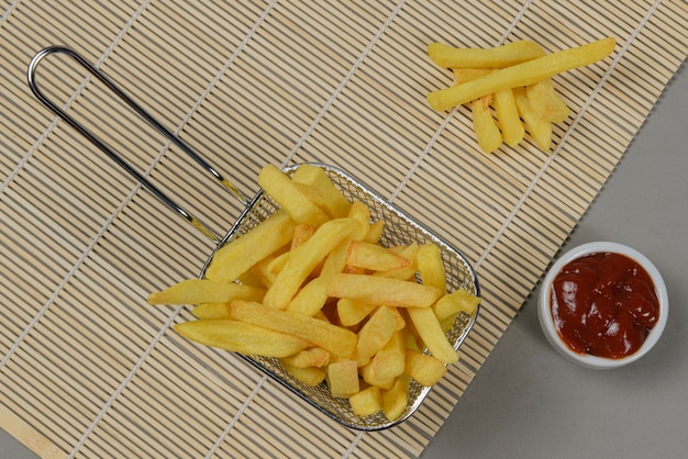 Porção de batatas fritas em uma cesta de metal.