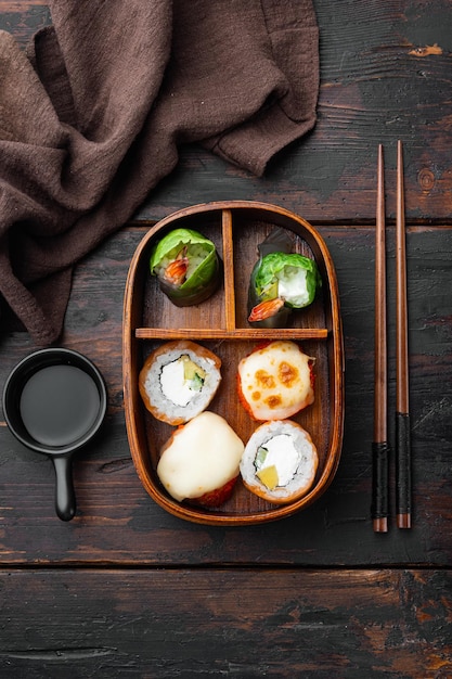 Porção de Comida Fresca em Caixa Bento Japonesa com Rolos de Sushi na velha mesa de madeira escura vista superior plana