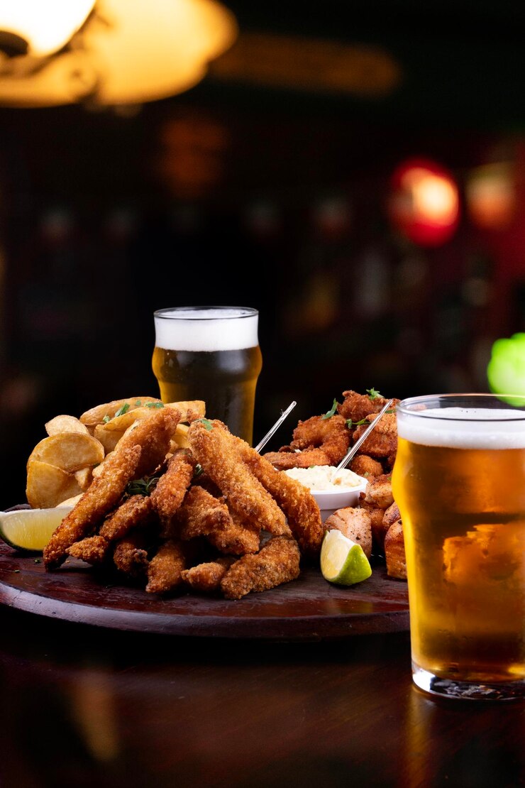 Foto porção de frutos do mar com peixe em panela e camarão e salmão grelhado com batatas fritas e dois copos de cerveja artesanal fundo desfocado em pub