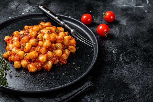 Porção de macarrão de batata nhoque italiano com molho de tomate. Fundo preto. Vista do topo. Copie o espaço.