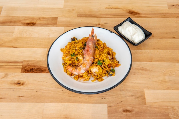 Porção de paella de arroz misto com legumes e frutos do mar Camarão grande mimado por cima do arroz e molho aioli para guarnecer