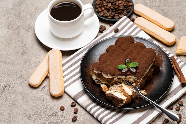 porção de sobremesa de tiramisu clássico e biscoitos savoiardi no fundo de concreto