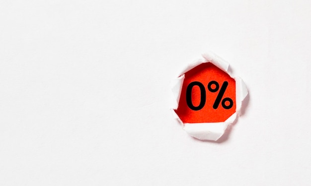 Porcentaje cero o 0 dentro del papel perforado rojo para la oferta especial de descuentos en tiendas por departamento de compras y concepto de tasa de interés bancaria