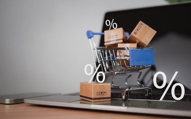 Porcentaje de ventas con carrito de compras y cajas colocadas en el teclado de la computadora Concepto de compras en línea