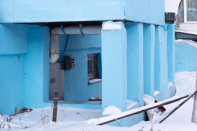 Porche azul con columnas, entrada a la casa, todo en la nieve.