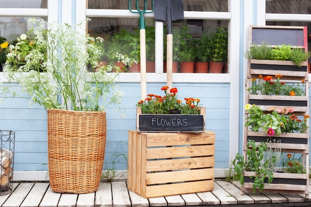 Porche de madera de la casa con plantas verdes y fachada de flores casa con herramientas de jardín y macetas de flores