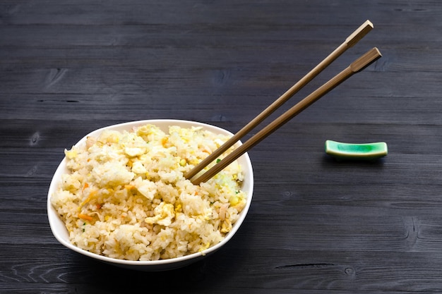 Porción de arroz frito con palillos en mesa oscura