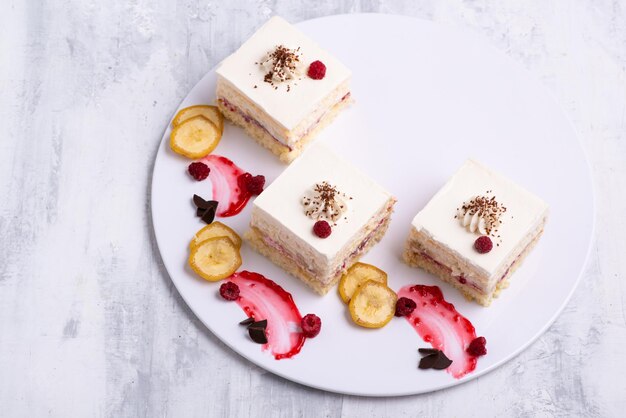 Porción de deliciosos trozos de pastel de vainilla de frutas en un plato blanco