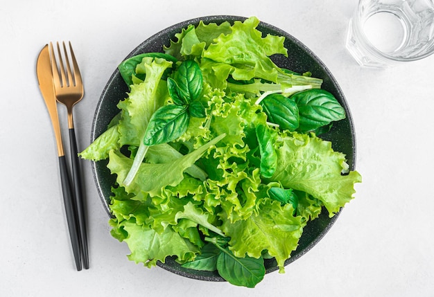 Una porción de ensalada hecha con una mezcla de hojas de albahaca fresca y lechuga sobre un fondo gris