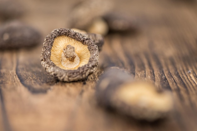 Porción de hongos Shiitake secos sobre fondo de madera enfoque selectivo