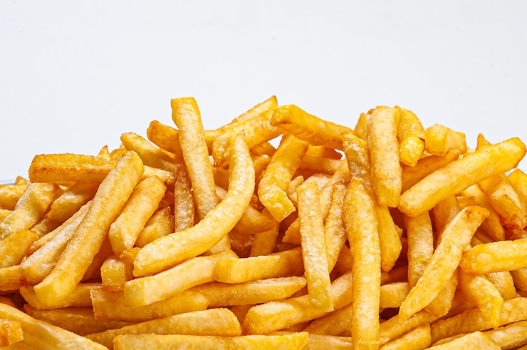 Foto porción de papas fritas servidas en un plato sobre fondo blanco.
