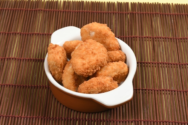 Una porción de pollo empanizado y crujiente en un cuenco de cerámica blanca. Comida rápida empanizada, frita o asada