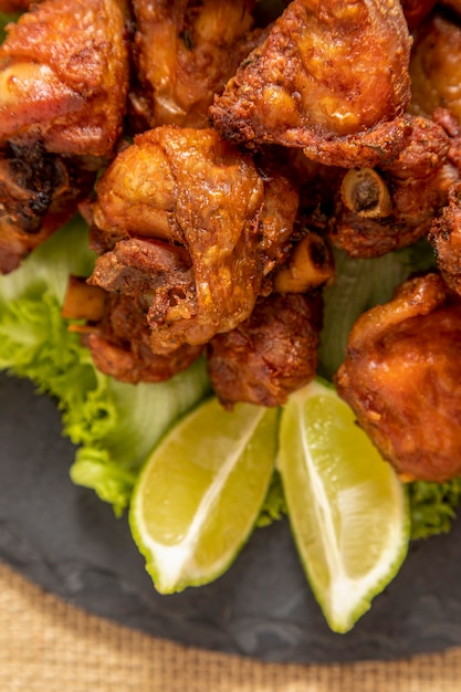 Foto porción de pollo frito en placa de piedra negra.