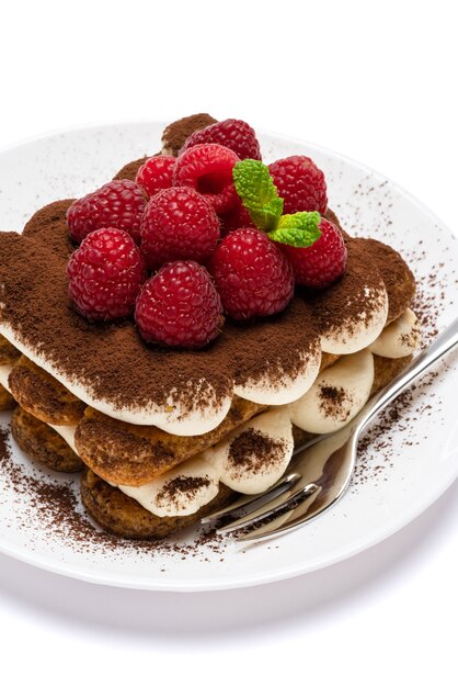 Porción de postre clásico tiramisú con frambuesas en una placa de cerámica