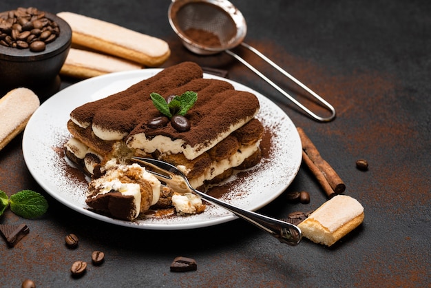 Porción de postre clásico tiramisú y galletas savoiardi sobre fondo de hormigón