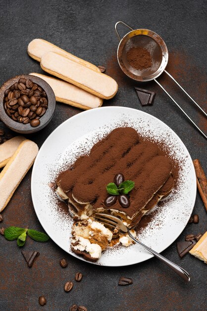 Porción de postre clásico tiramisú y galletas savoiardi sobre fondo de hormigón