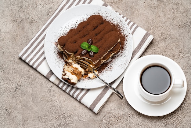 Porción de postre clásico tiramisú y una taza de café espresso fresco sobre fondo de hormigón