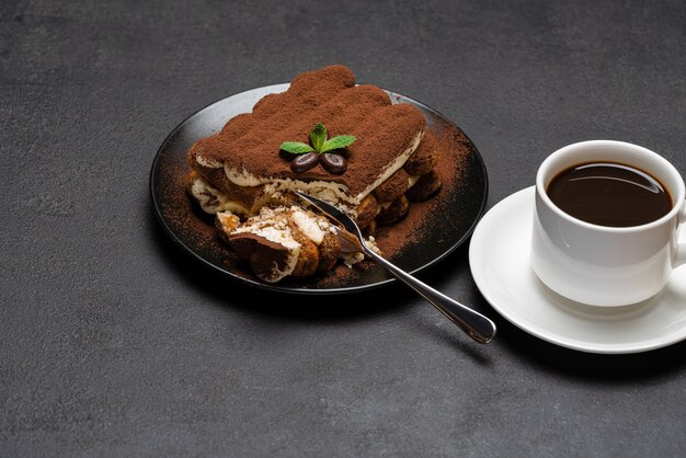 Porción de postre tiramisú clásico y una taza de café espresso fresco sobre fondo de hormigón o mesa