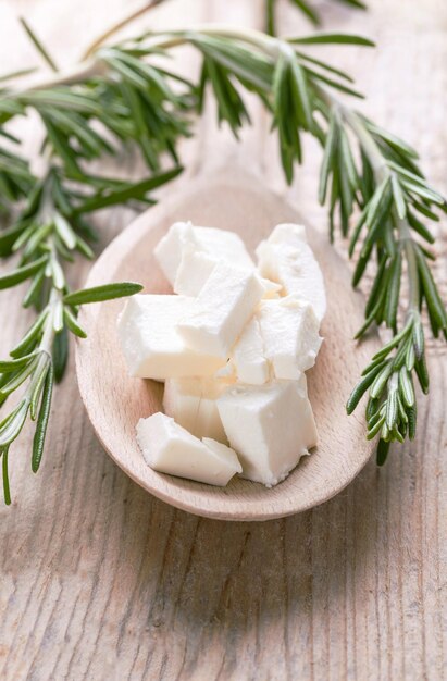 Porción de queso feta en una cuchara de madera con romero