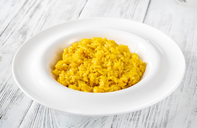 Porción de risotto de azafrán en la mesa de madera