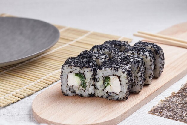 Una porción de rollos en un soporte, comida japonesa, sushi en la mesa, palillos chinos, fondo claro