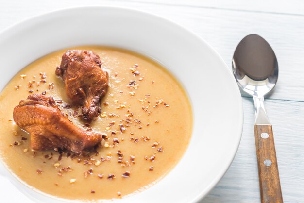 Porción de sopa de crema de guisantes con alitas de pollo ahumadas