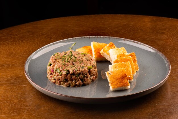 Porción de tartar de carne cruda con primer plano de especias con vista tostada