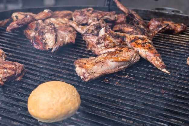 Porciones variadas de carne cocida y un panecillo recién horneado asado a la parrilla sobre brasas