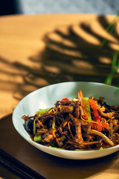 Porco agridoce com legumes wok em uma tigela branca. Cozinha chinesa.