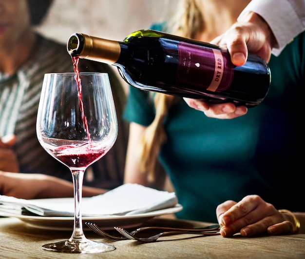 Poring garçom servindo vinho tinto para clientes em um restaurante