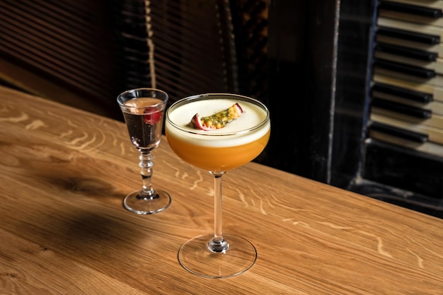 Pornostar-Martini-Cocktail mit Passionsfrucht und Wodka am Holztisch in der Bar oder im Restaurant, horizontales Foto