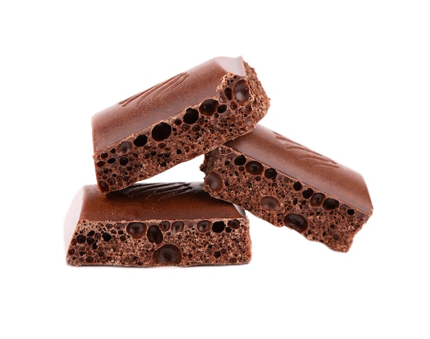 Poröse Schokoladenstücke lokalisiert auf weißem Hintergrund. Schwarze kohlensäurehaltige Schokolade.