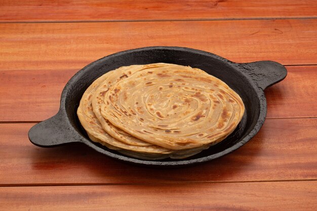 Porotta oder Lachha Paratha geschichtetes Fladenbrot aus Weizenmehl, das in einer gusseisernen Pfanne angeordnet ist