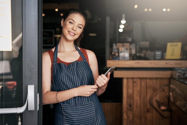 Porque necesitas un descanso de tu rutina diaria Retrato de una joven segura de sí misma parada en la puerta de una cafetería