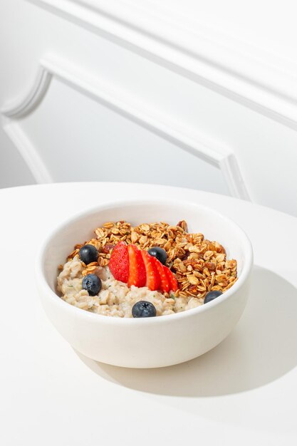 Porridge con arándanos y avena en una mesa blanca soleado luz dura desayuno saludable