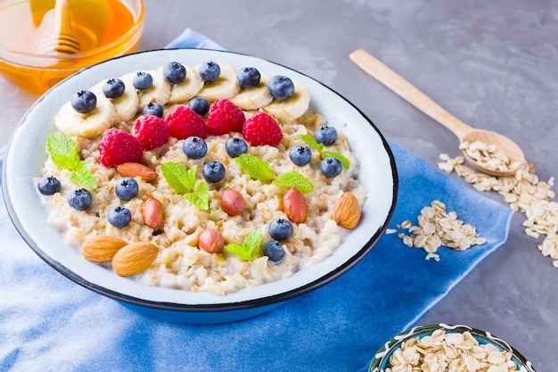 Porridge de avena con bayas frutas y miel en fondo gris saborosa avena con frambuesas