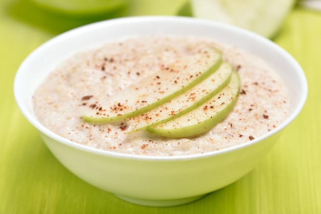 Porridge de avena con rebanadas de manzana y canela en un cuenco blanco