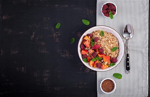 Porridge de aveia com framboesa e pêssego em fundo escuro Café da manhã saudável Comida vegetariana Vista superior