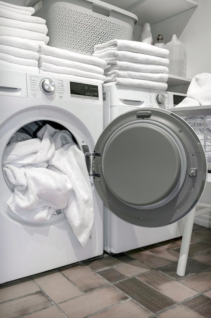 Porta aberta da máquina seca no hotel com toalhas brancas na lavanderia
