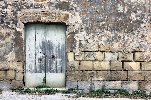 Porta antiga de madeira cinzenta maltesa típica na parede de calcário de Malta Conceito de arquitetura vintage tradicional maltesa de vista para a rua