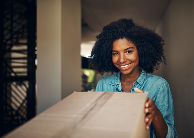 Porta da frente da mulher africana e caixa para entrega de comércio eletrônico ou serviço em retrato com sorriso em casa Pacote de menina e feliz pela experiência do cliente da cadeia de suprimentos e carga para correio no apartamento