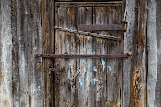 Porta de celeiro de madeira velha com cadeados de ferro e bandas de reforço de aço oxidado