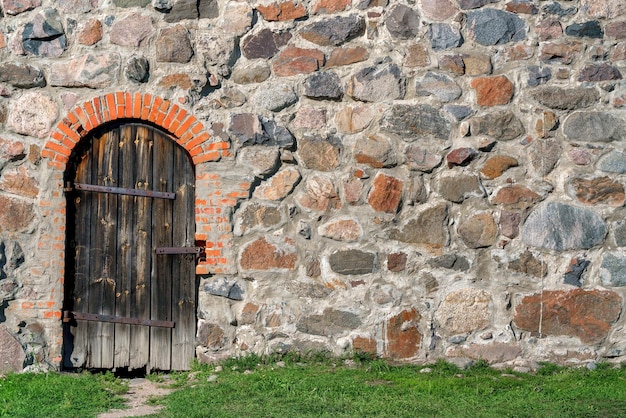 Porta de madeira em uma parede de pedras irregulares Fundo de construção vintage