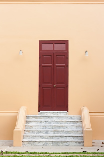 Porta de madeira marrom antiga na parede laranja