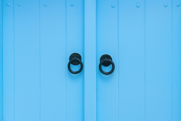 Foto porta de madeira vintage pintada de azul com alças metálicas em close-up arquitetura cicládica em santorini, grécia