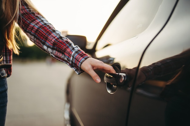 Porta do carro aberta de mão feminina, conceito de motorista iniciante