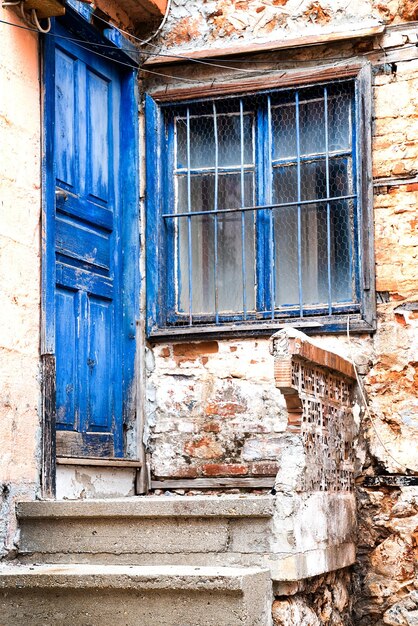 Porta e janela pintadas de azul na fachada da antiga estrutura vertical da casa da aldeia