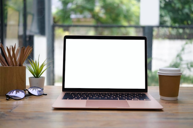 Porta-lápis de xícara de café de computador portátil e planta de casa na mesa de madeira